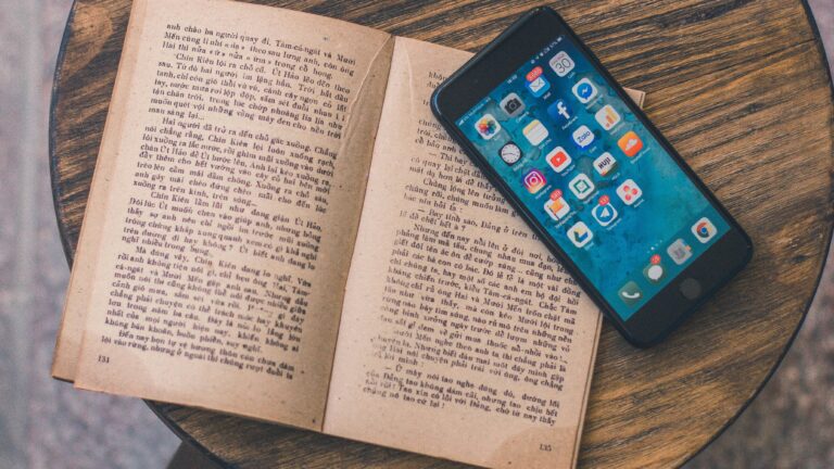 ein Buch und ein Smartphone auf einem Holztisch