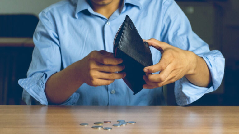 Eine leere Geldtasche, Hände eines Mannes, wenige Münzen.