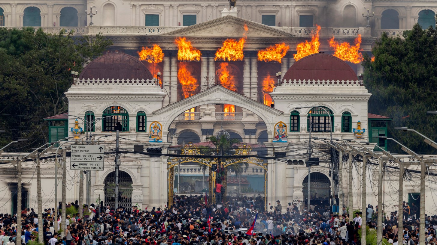 Der nepalesische Regierungspalast steht in Flammen, während sich eine große Menschenmenge vor seinen Toren sammelt.