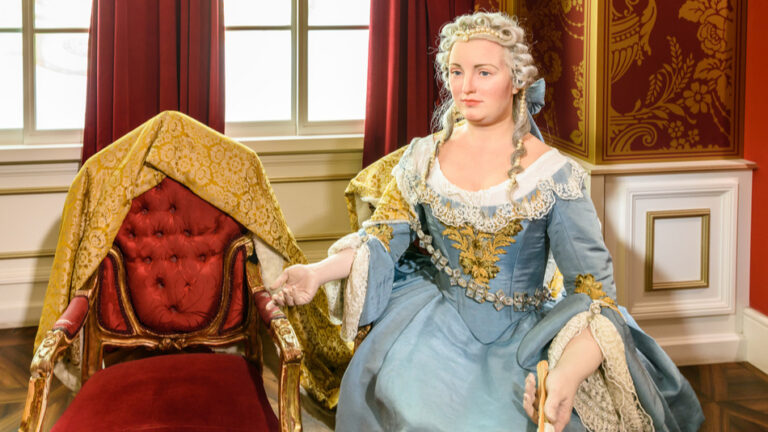 Das Bild zeigt die dunkle Bühne des Ronachers mit dem rosa, hell erleuchteten Schriftzug des Maria Theresia Musicals.