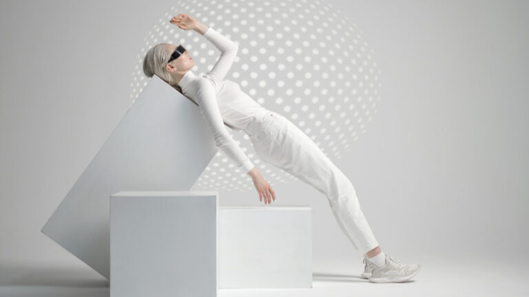 Eine Frau mit kurzen Haaren, in qweißen Kleidern mit schwarzer Sonnenbrille