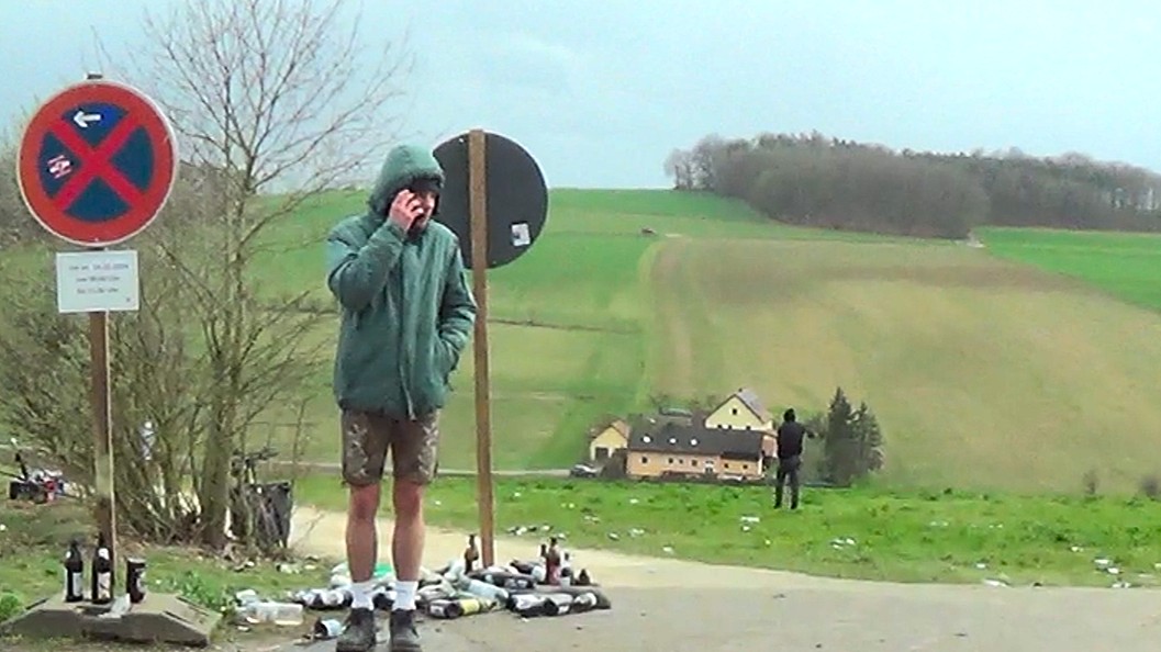 Landschaftsaufnahme des Adlerbergs. Erschöpfte Besucher und Flaschen bestimmen die Szenerie.