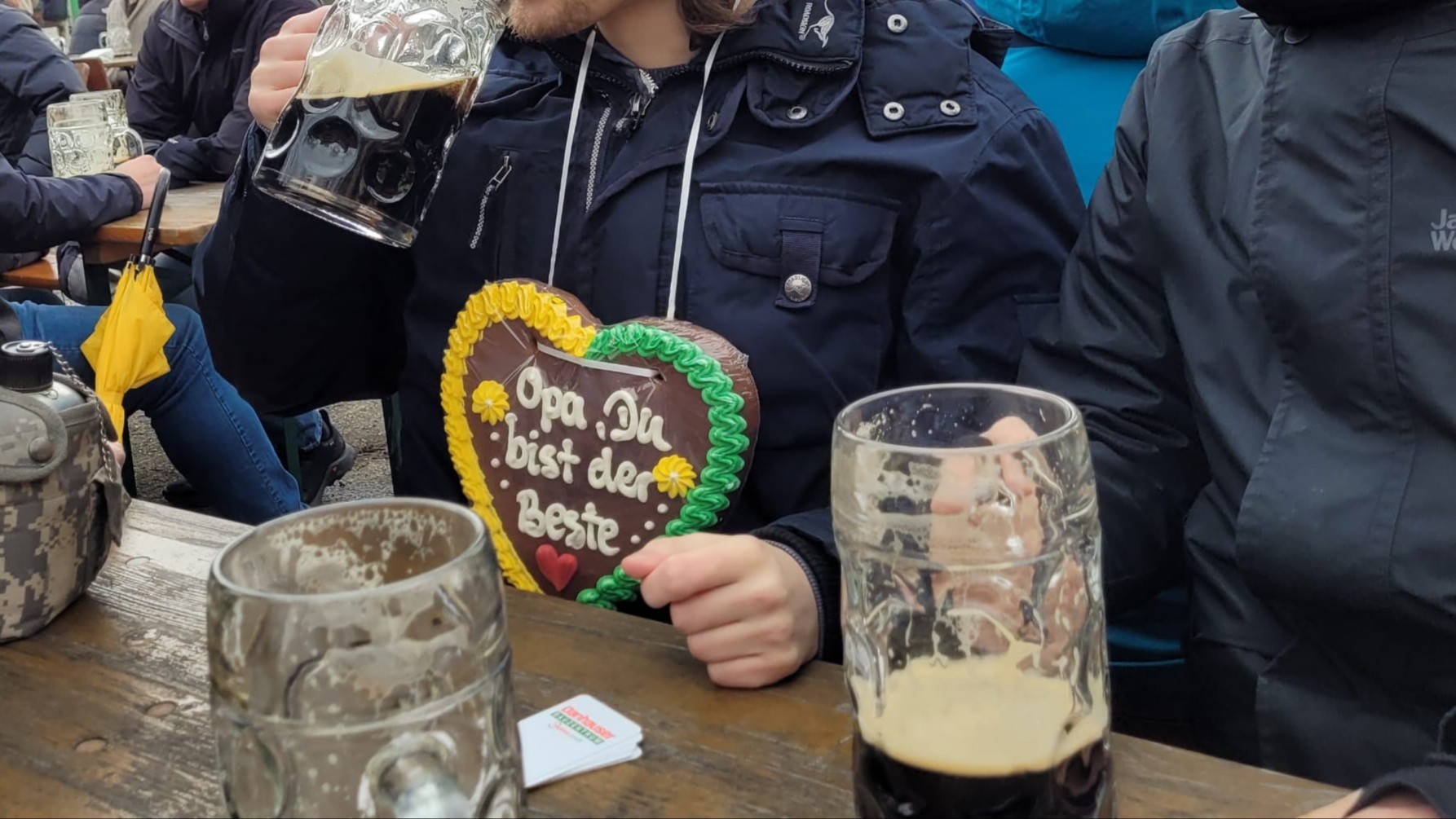 Biertisch-Szene am Palmator. Ein Besucher hat ein Lebkuchenherz mit der Aufschrift "Opa, du bist der Beste" um den Hals.