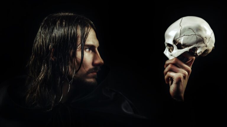 Das Bild zeigt einen Mann, der eine Maske in der Hand hält. Es ist aus einem Theaterstück.