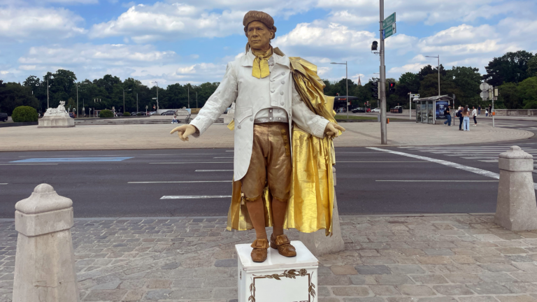 Charles steht vor dem Schloss Schönbrunn auf einem Podest. Sein goldenes Kostüm stellt Mozart dar.